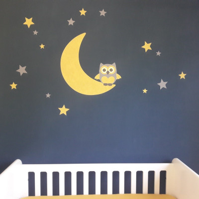 Behang muursticker babykamer uil op de maan okergeel op donkere muur.