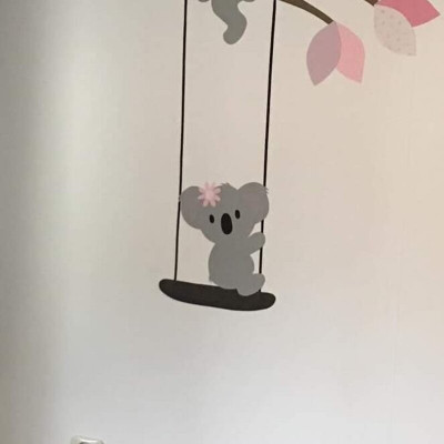 Behang muursticker zittend koalabeertje op schommel met bloem.