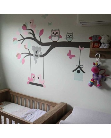 Behang muursticker sierlijke uilentak groen roze op een beige muur.