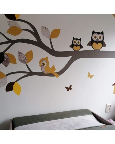 Behangsticker babykamer sierlijke uilentak okergeel boven de commode met groen tinten.