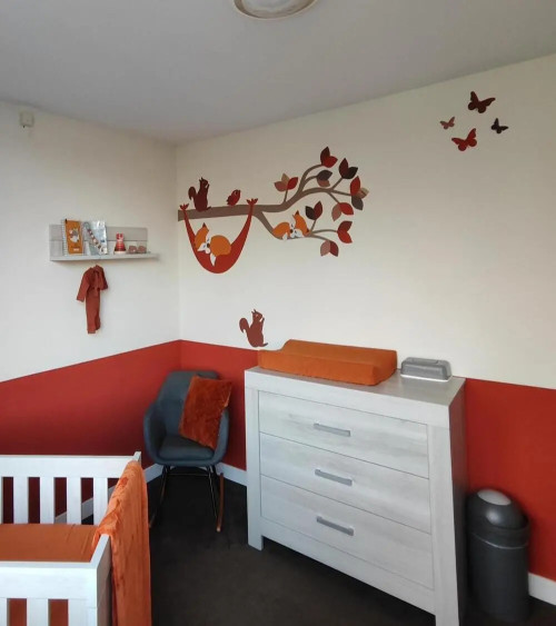 Muursticker babykamer tak met vosje in hangmat in natuurlijke groentinten.