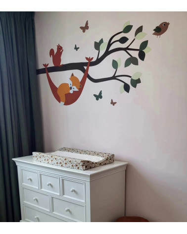 Muursticker babykamer tak met vosje in hangmat in natuurlijke groentinten.