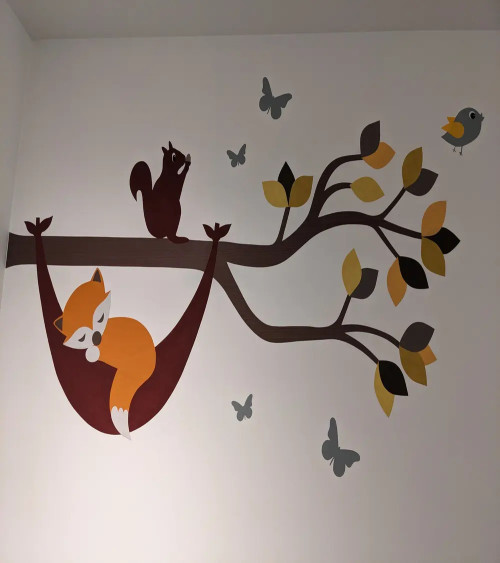 Muursticker babykamer tak met vosje in hangmat in natuurlijke groentinten.