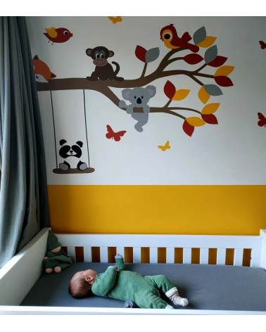 Behangsticker babykamer met een tak met vrolijke dieren in de kleuren okergeel en rood.