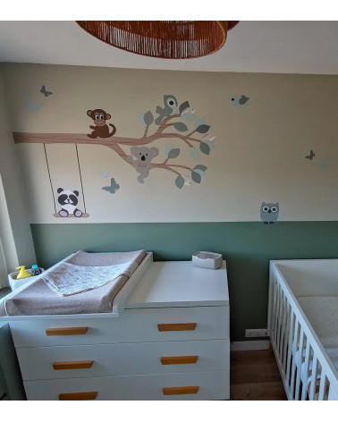 Muursticker babykamer tak met vrolijke dieren oud groen op een muur met early dew.