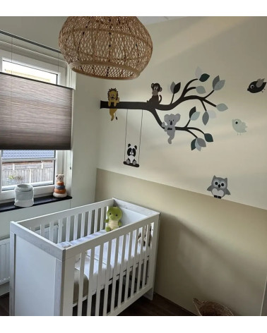 Behangsticker tak met vrolijke dieren in groen, zwart en wit in een beige babykamer.