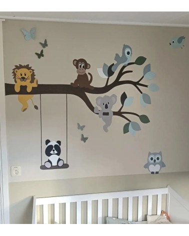 Behangsticker tak met vrolijke dieren in groen, zwart en wit in een beige babykamer.