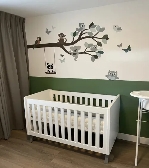 Behangsticker tak met vrolijke dieren in een groene babykamer.