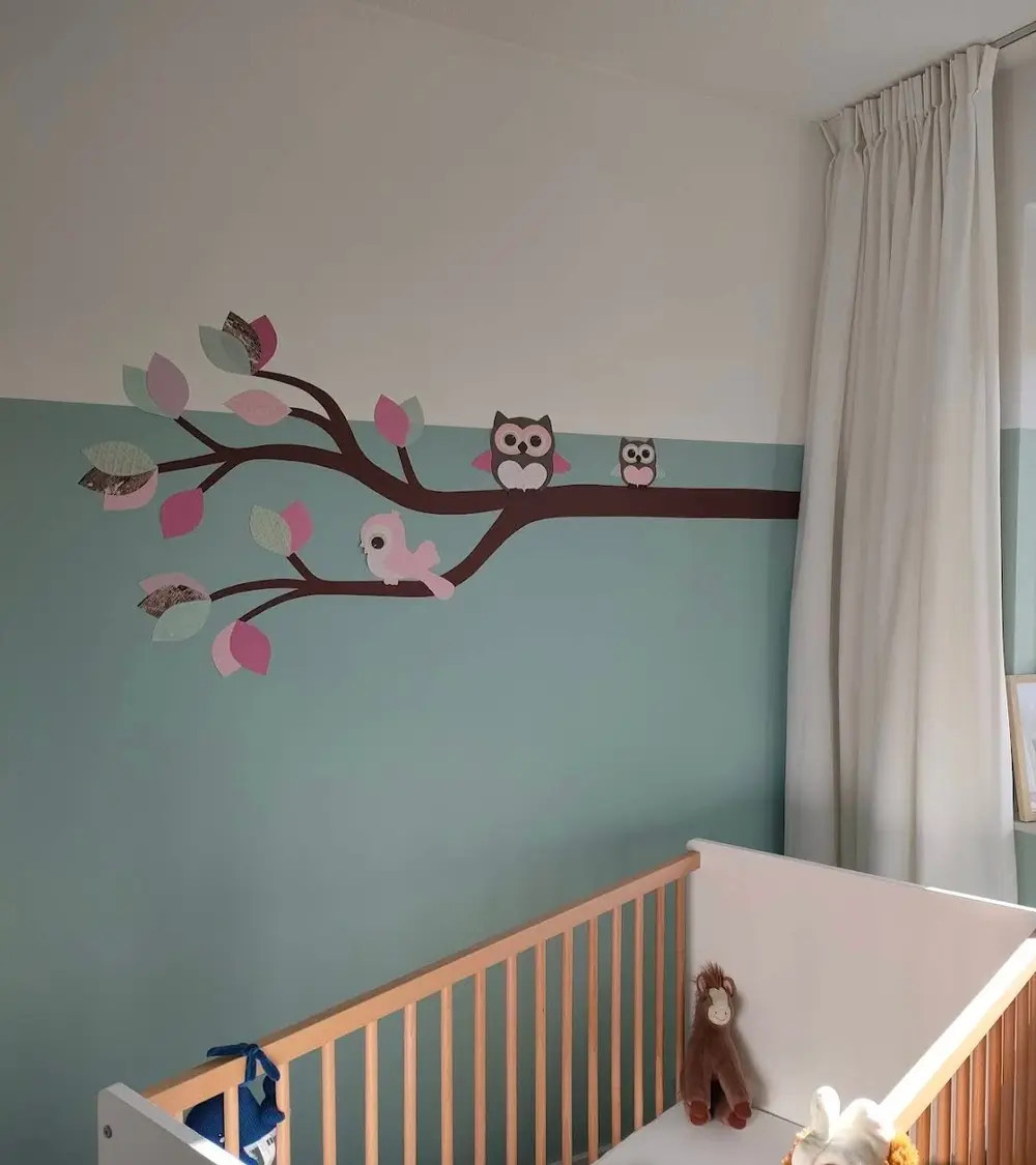 Behang sticker baby meisjeskamer roze en groene tak met uiltjes en vogel.