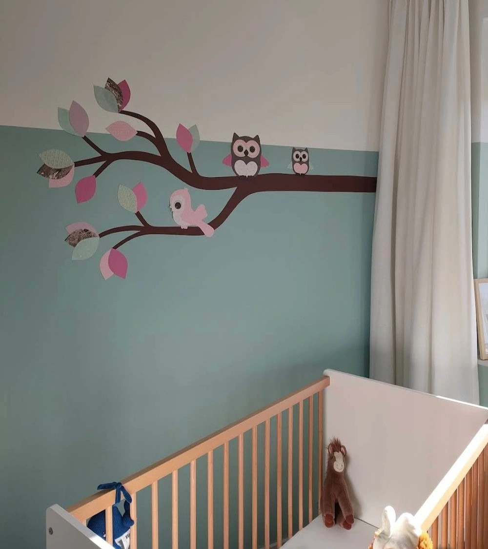 Behangsticker meisjeskamer met een sierlijke uilentak in zacht roze en mintgroen.
