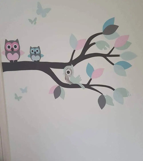 Behangsticker meisjeskamer sierlijke uilentak in roze, mintgroen en lichtblauw.