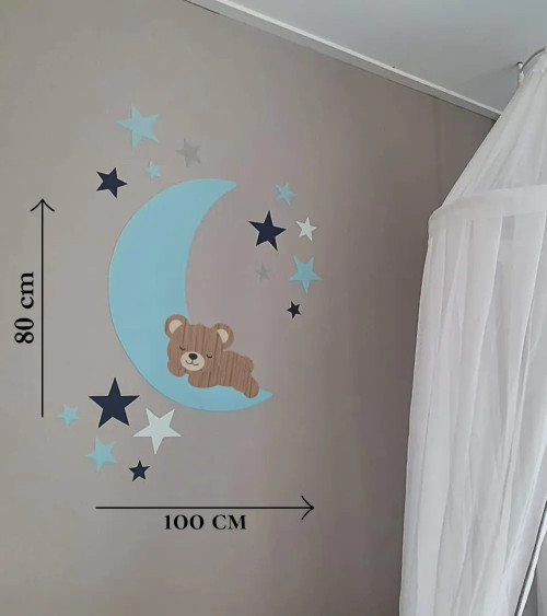 Behang muursticker babykamer slapend teddybeertje op een lichtblauwe maan met donker- en lichtblauwe sterren.