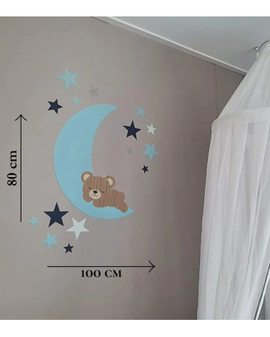 Behang muursticker babykamer slapend teddybeertje op een lichtblauwe maan met donker- en lichtblauwe sterren.
