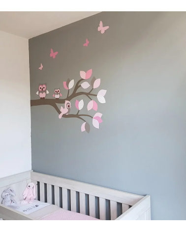 Behangsticker roze sierlijke uilentak op een grijze muur in een meisjesbabykamer.