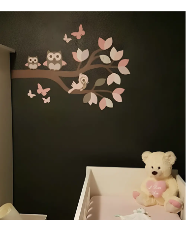 Muursticker tak met roze uilen op een zwarte muur in de meisjes babykamer.