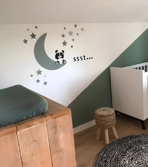 Groene babykamer met een oudgroene pandabeer op maan muurdecoratie.