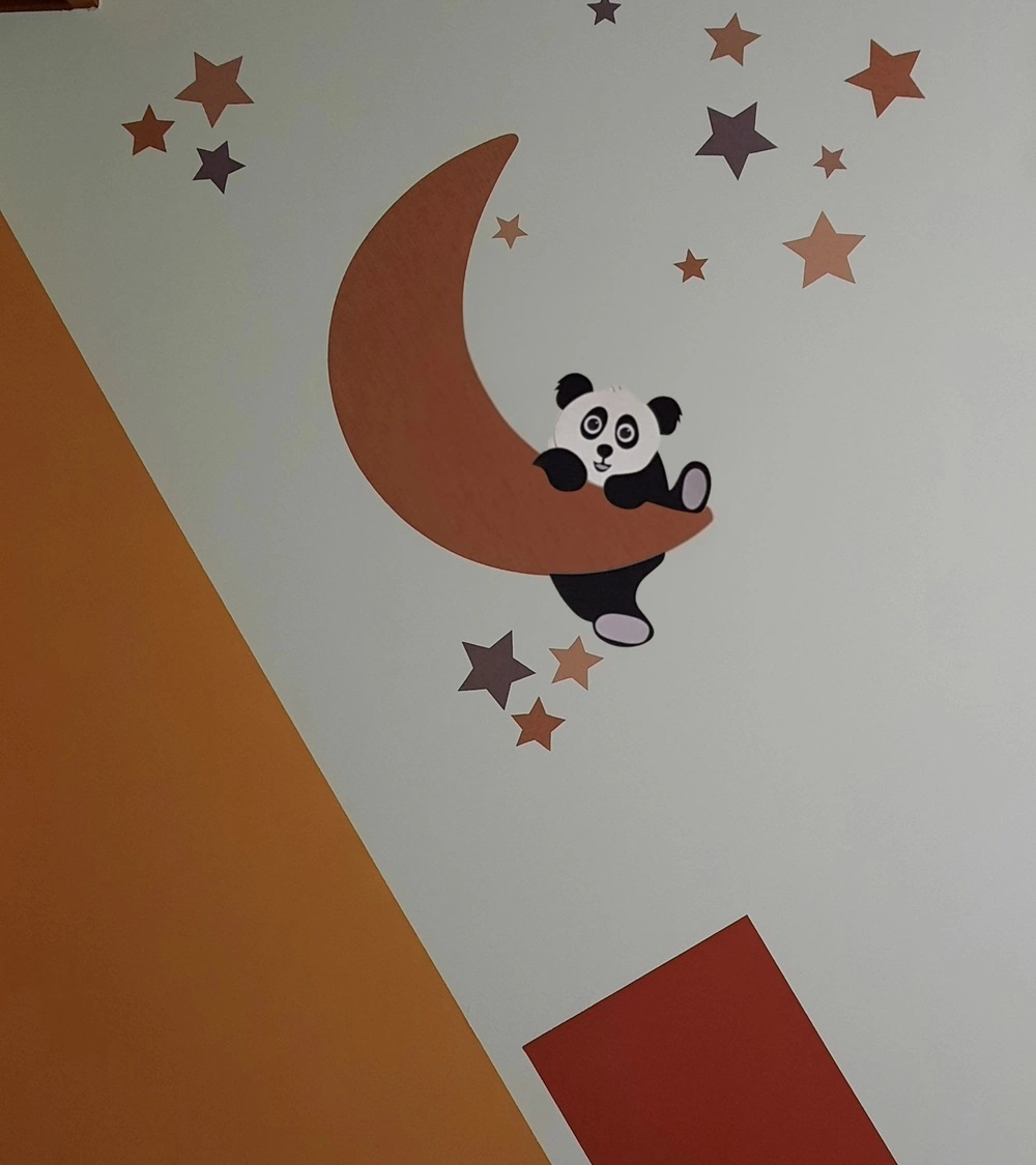 Babykamer behangsticker met een hangende pandabeer op een terracotta maan.