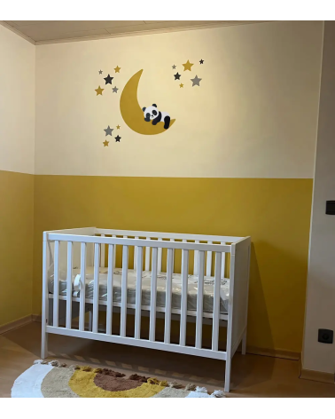 Een okergele babykamer met een behangsticker met een slapende pandabeer op een maan.