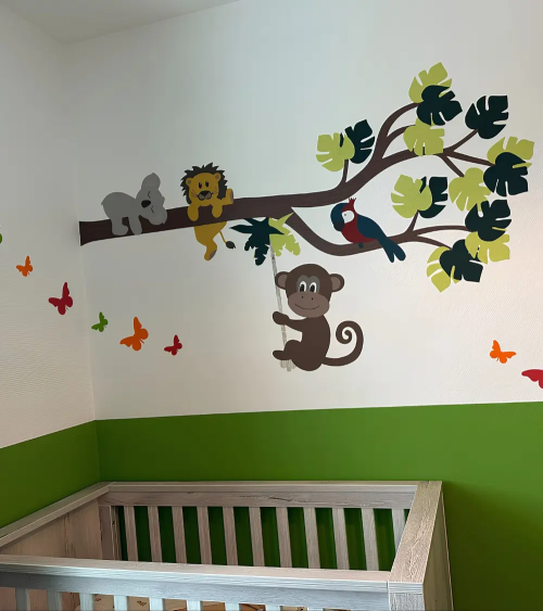 Jungle tak behangsticker met vrolijke jungle dieren boven het ledikantje in een lime groene babykamer.