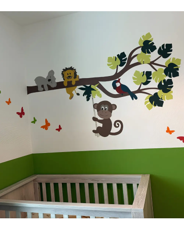 Jungle tak behangsticker met vrolijke jungle dieren boven het ledikantje in een lime groene babykamer.
