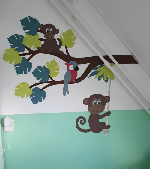 Muursticker babykamer Jungle tak met jungledieren en groene jungle bladeren.