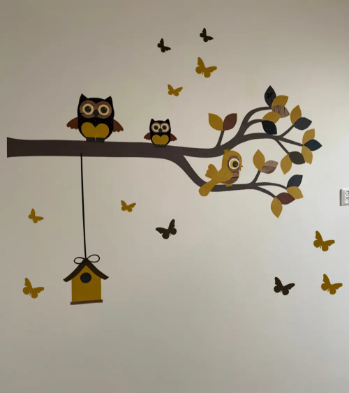 Behangsticker sierlijke uilentak in warm oker en bruin, als muurdecoratie in een neutrale babykamer.