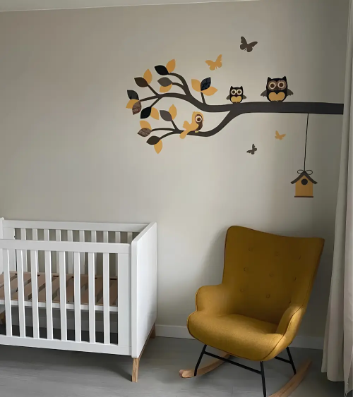 Behangsticker neutrale babykamer tak met uiltjes in okergeel, zwart en bruin.