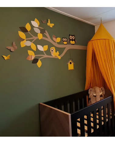 Behangsticker sierlijke uilentak okergeel op een donkergroene muur in de babykamer.