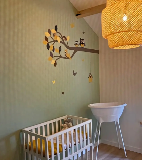 Behangsticker okergele uilentak in groene babykamer.