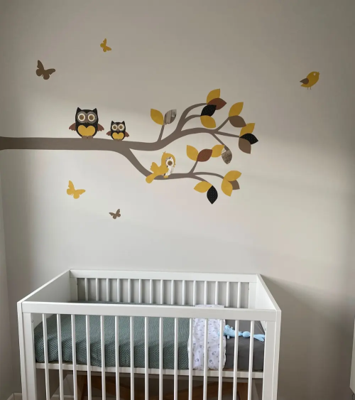 Muursticker babykamer van behang tak met uilen okergeel en bruin.