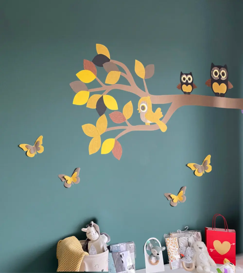 Muursticker van behang tak met uilen okergeel in een donkergroene babykamer.