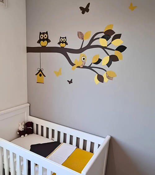 Behang muursticker beige babykamer sierlijke uilentak okergeel met vlinders en vogelhuisje.