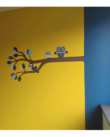 Sierlijke uilentak licht- en donkerblauw in een okergele jongensbabykamer.