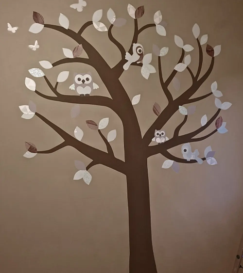 Neutrale boom muurdecoratie kinderkamer met mintgroene bladeren op een bruine muur.