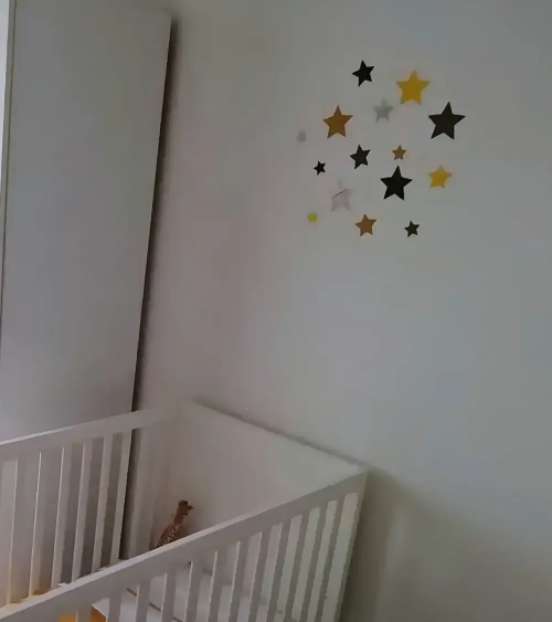 Set sterren behangstickers babykamer okergeel boven ledikantje.