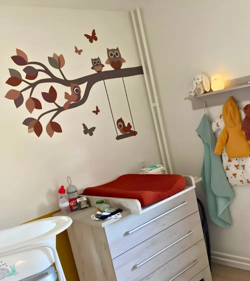 Behangsticker babykamer sierlijke uilentak roestbruin en terracotta met schommel.