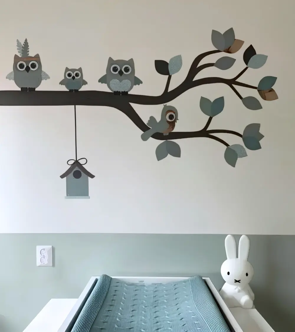 Neutrale babykamer decoratie, een sierlijke uilentak oudgroen met een indianen uil, vogelhuisje en vlinders boven de commode.