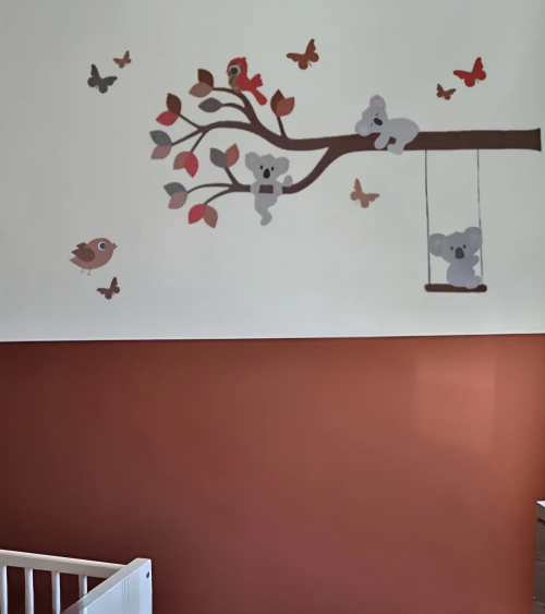 Muurdecoratie babykamer tak met koalabeertjes, een schommel, vlinders en vogeltje in terracotta, rood en roestbruin.