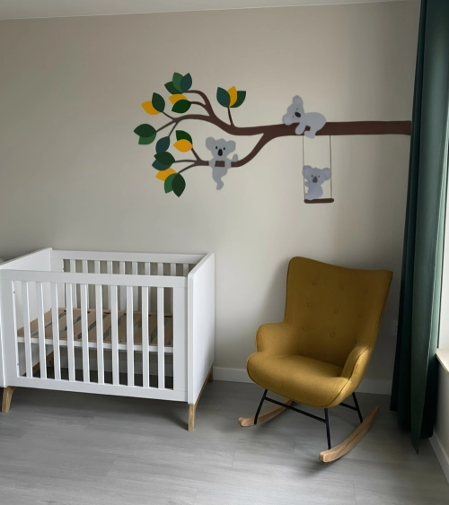 Behangsticker tak met koalaberen in donkergroen en oker in een beige jongensbabykamer.