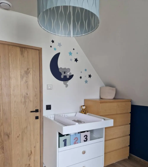 Jongenskamer behangsticker van een klimmende koala op een donkerblauwe maan met sterren.