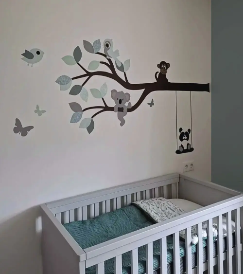 Behangsticker van een tak met vrolijke dieren in mintgroen en oudgroen in een lichte neutrale babykamer.