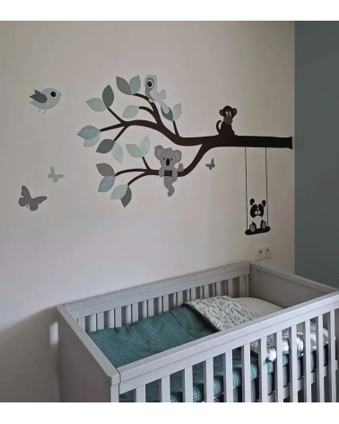Behangsticker van een tak met vrolijke dieren in mintgroen en oudgroen in een lichte neutrale babykamer.