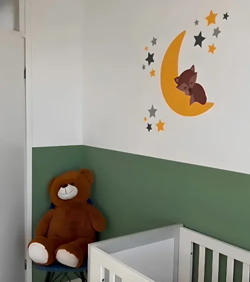 Groene babykamer met een okergele maan en sterren behangsticker met een slapend vosje