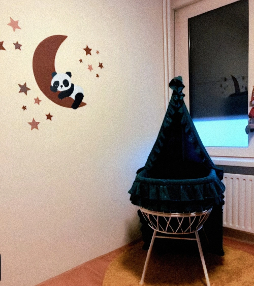 Slapende pandabeer op de maan roest boven het wiegje in de babykamer.