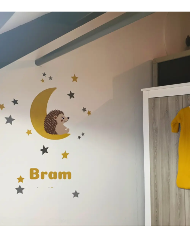 Egel behangsticker op een okergele maan met sterren en naamsticker in een neutrale babykamer.