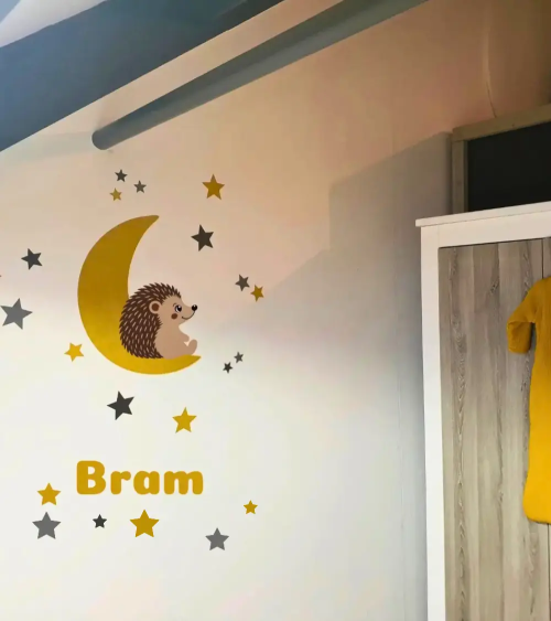 Okergele maan behangsticker voor de kinderkamer met naamletters, een egeltje en sterren.