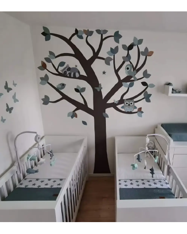 Groene tweeling babykamer met oudgroene behangboom met bosdieren, zoals een uil, wasbeer en vogels.