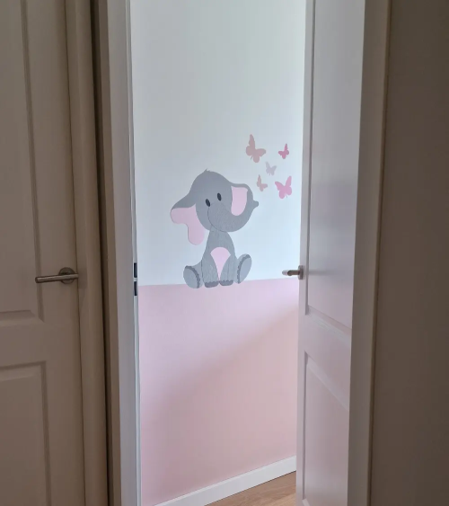 Roze meisjeskamer met roze baby olifant wanddecoratie en vlinders.
