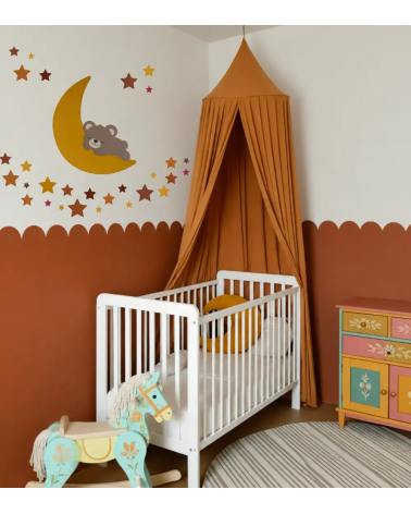 Een babykamer in vrolijke kleuren oranje, oker, terracotta met een slapende teddybeer op de maan behangsticker en sterren.