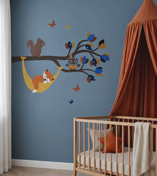 Muurdecoratie van een bosdierentak met een vosje in een hangmat in een donkerblauwe en terracotta babykamer.